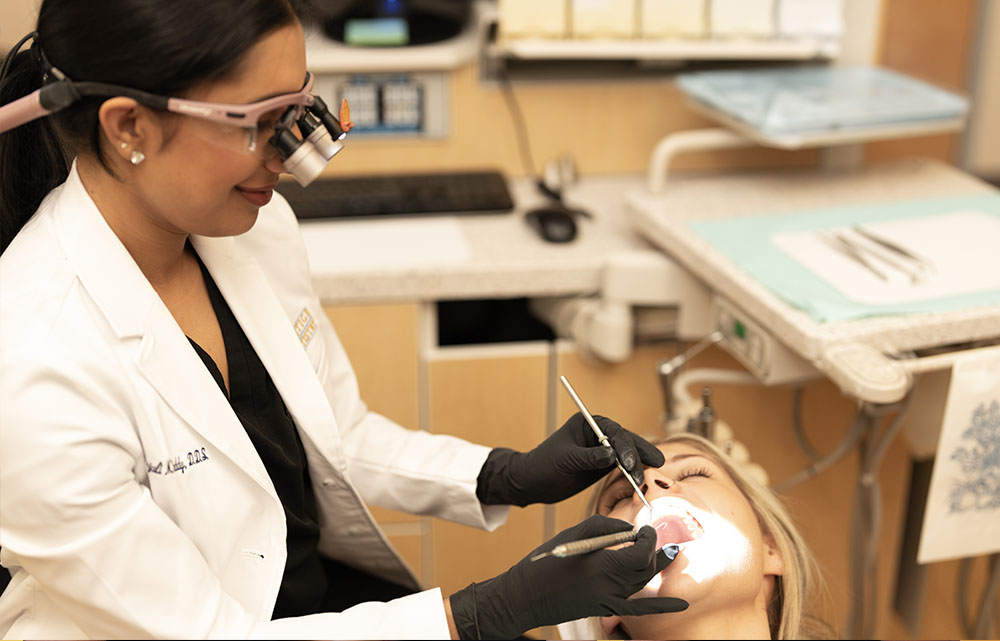 A dental hygienist performing oral care on a patient with the assistance of a dentist.