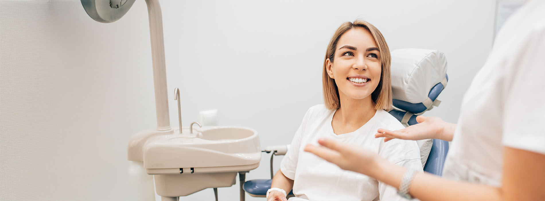 The image features a woman seated in a dental chair, receiving dental care from a professional who appears to be conducting an examination.