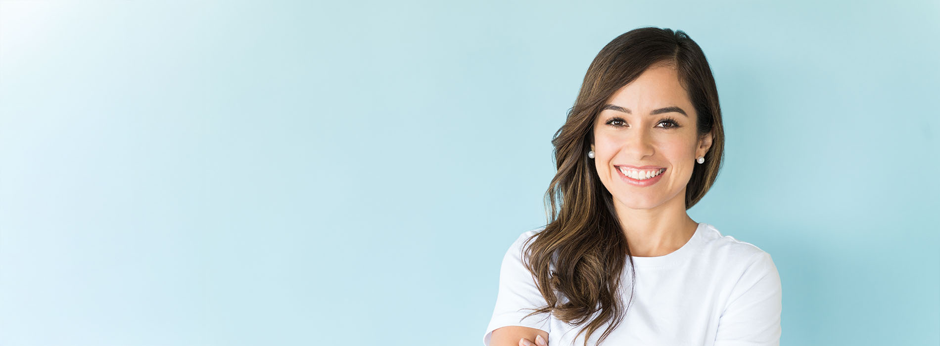 The image shows a woman posing with a smile against a light blue background, wearing a white top.
