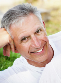 Smiling older man from New Port Richey, FL shows off his new porcelain crowns and dental bridges.